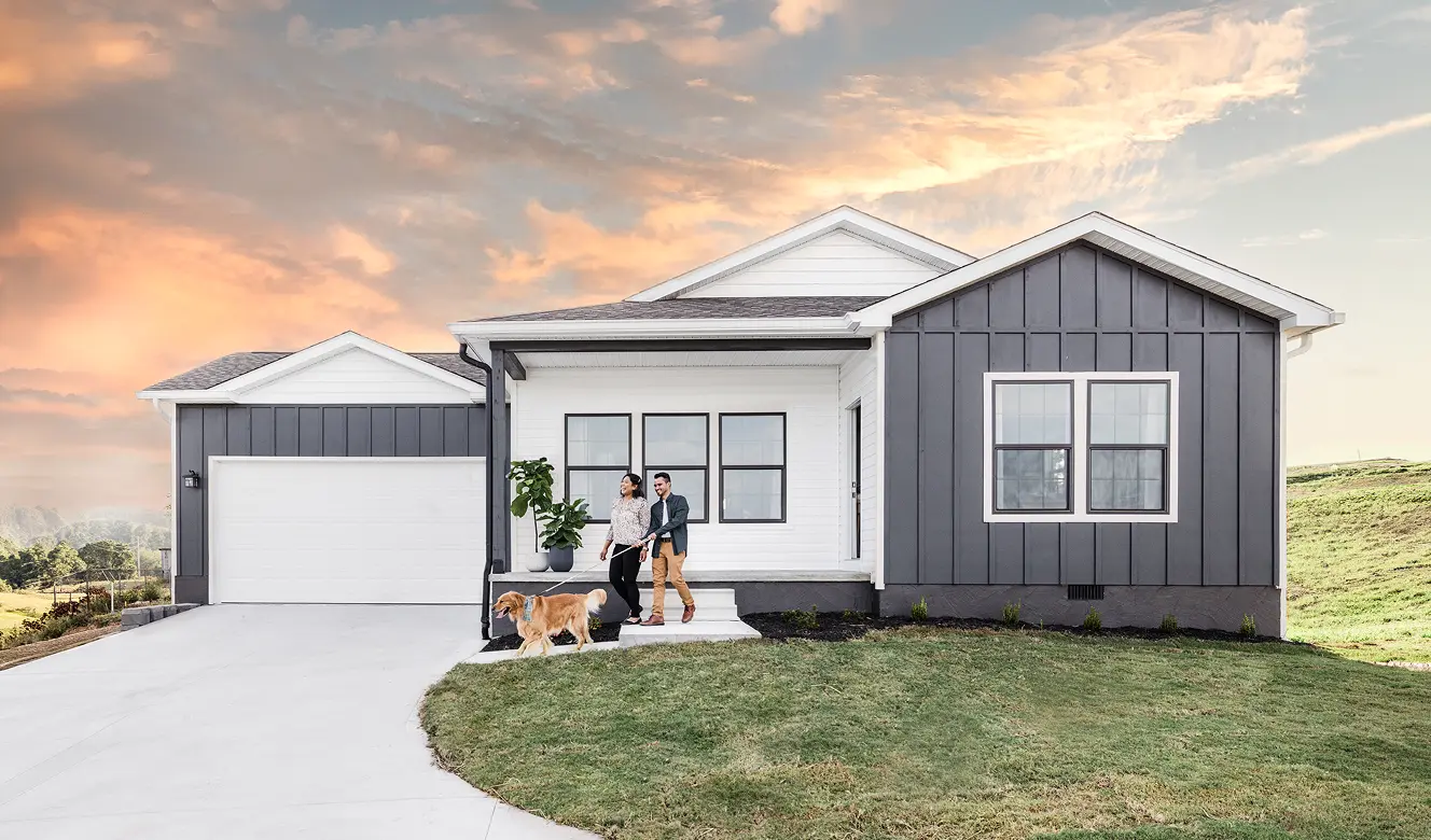 A dark gray modern Clayton home with a covered front porch and two-car garage at dusk.